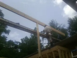 Carpenter setting a ridge beam over a new addition frame — Ice Dam Removal by Roofing Brothers in Nickerson