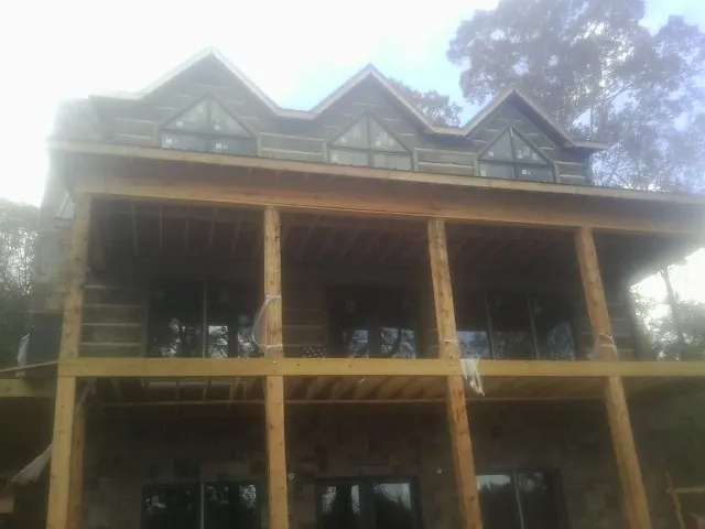 Dormers and porch framing on a large log home under construction — Roof Coating work by our crew in Nickerson