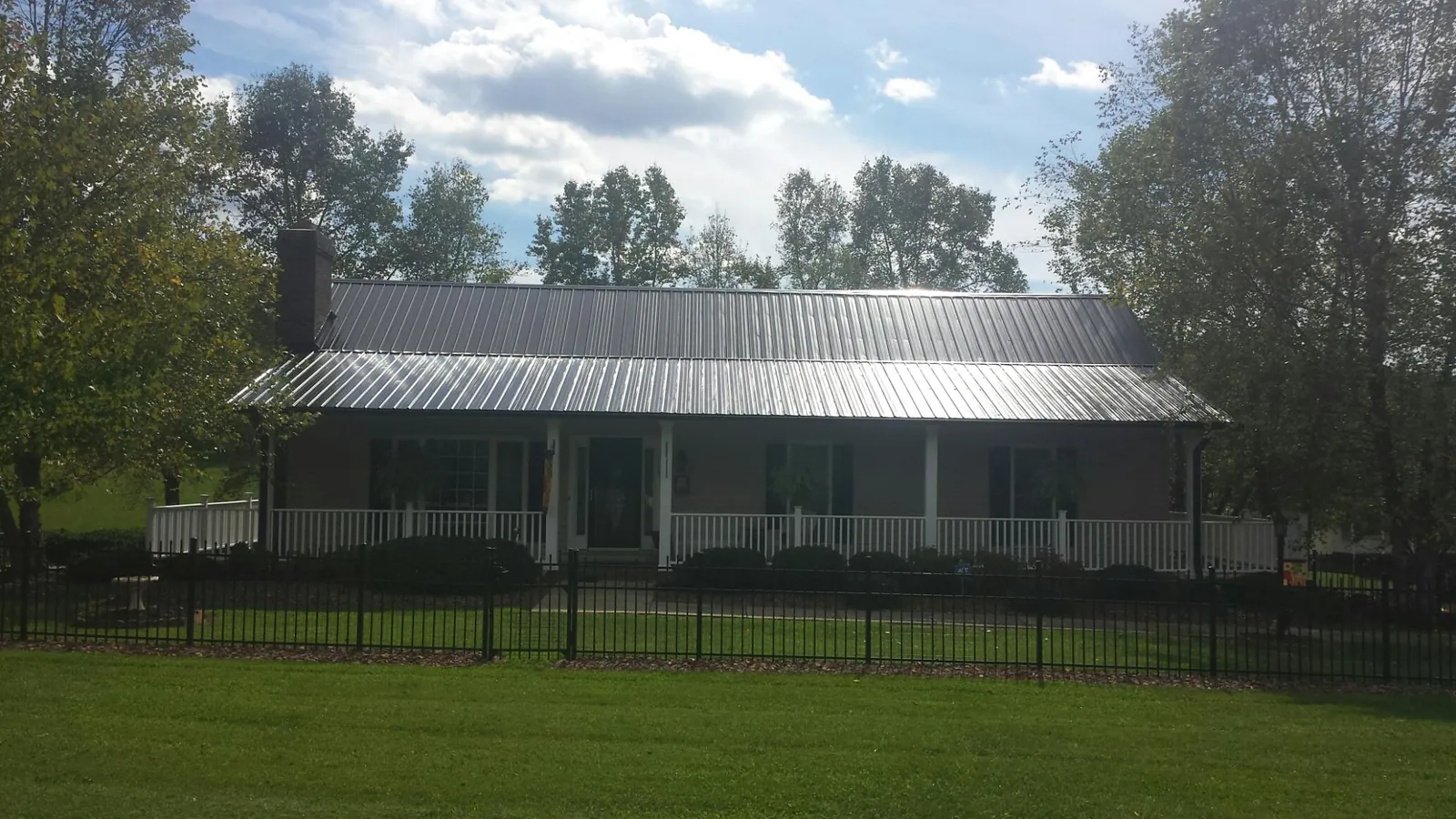 Gray metal roof on a brick ranch with a full width front porch — Gutter Guard Installation work by our crew in Nickerson
