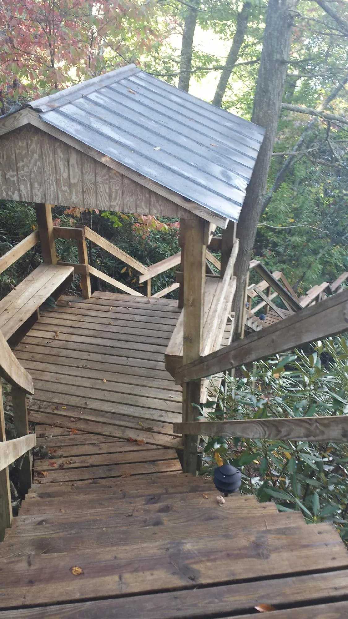 Metal roofed shelter over wooden steps on a wooded walkway — Skylight Repair & Installation work by our crew in Nickerson